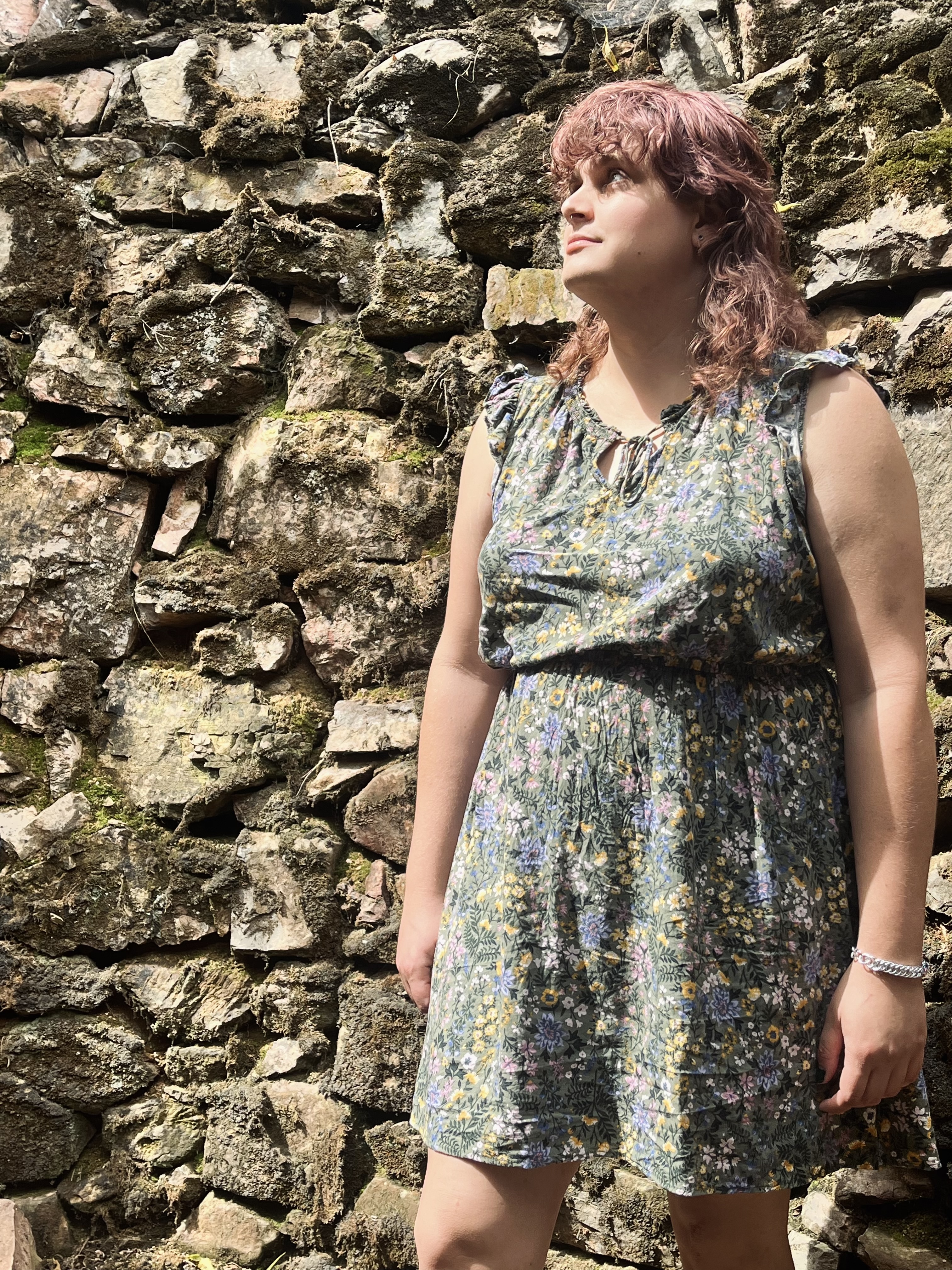 Bri in a green dress in front of a stone wall.